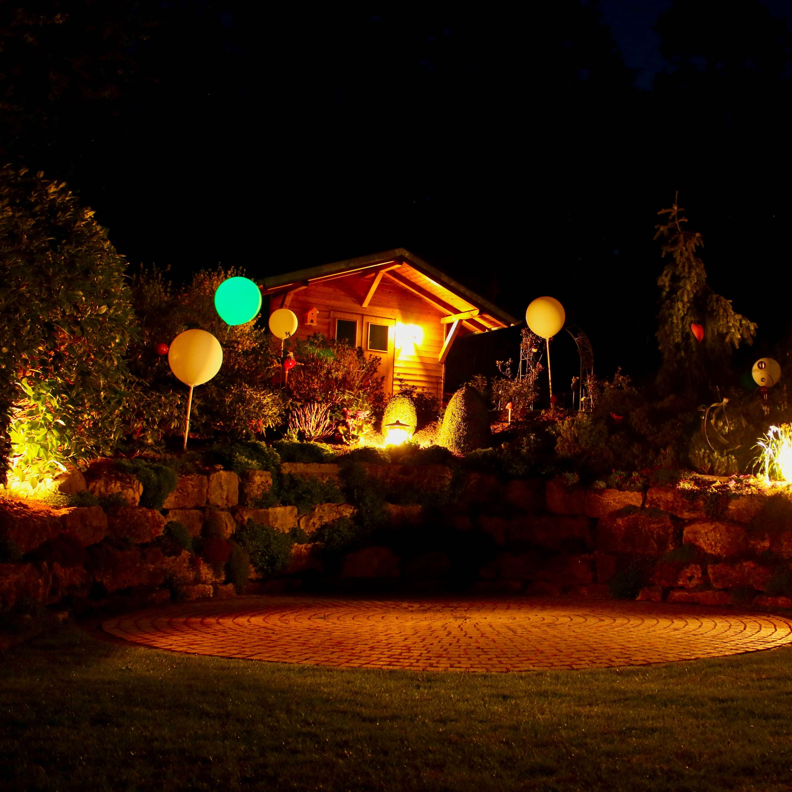 In einem dunklen Garten leuchtende Riesenballons, vorbereitet für eine Gartenparty