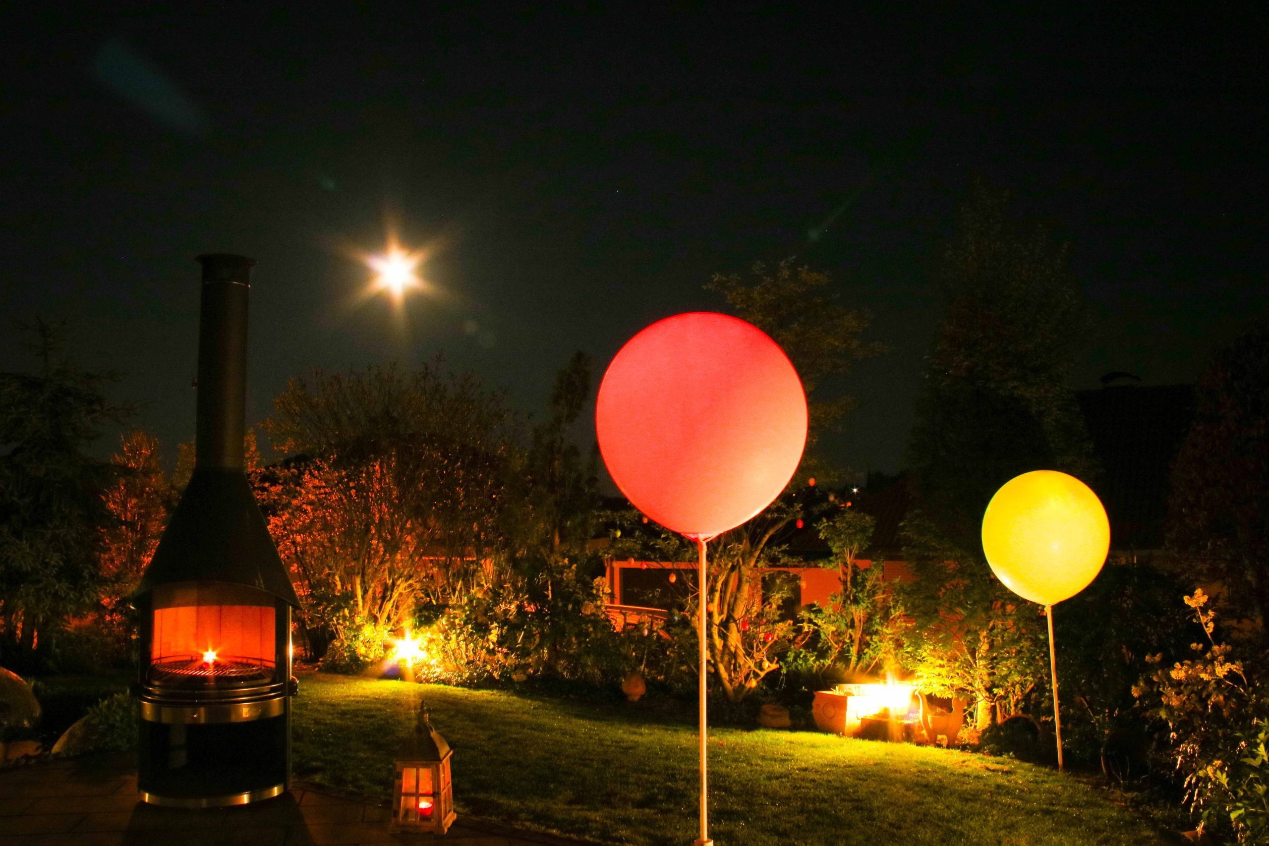 Im Dunkeln beleuchteter Garten mit leuchtenden Ballons
